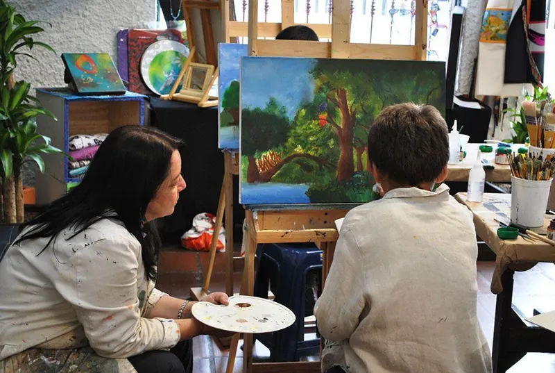 Artistas pintando cuadros en un taller de la galería El Arte Crea