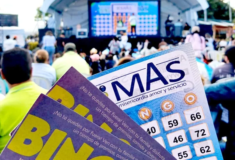 Cartones del Bingo MAS en primer plano y el público del evento al fondo