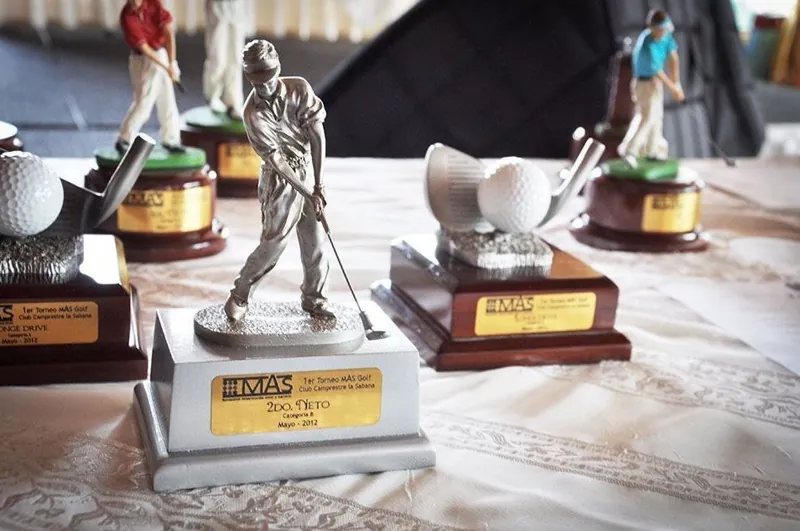 Trofeos del Torneo MAS golf sobre una mesa