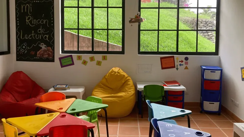 Rincón de lectura con puffs de colores y mesas para niños en la sede de Armenia