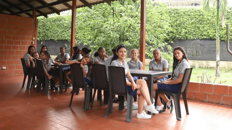 Jóvenes conversando alrededor de una mesa en el comedor al aire libre de la sede de Cali