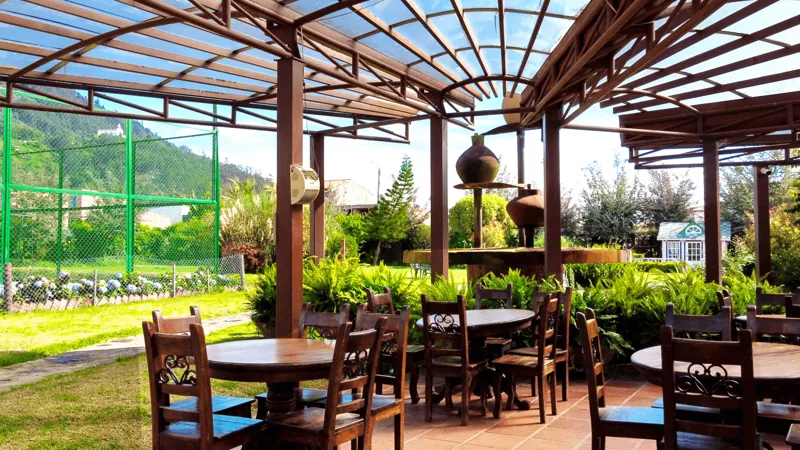 Comedor bajo una pérgola con vista al jardín en la sede de Chía