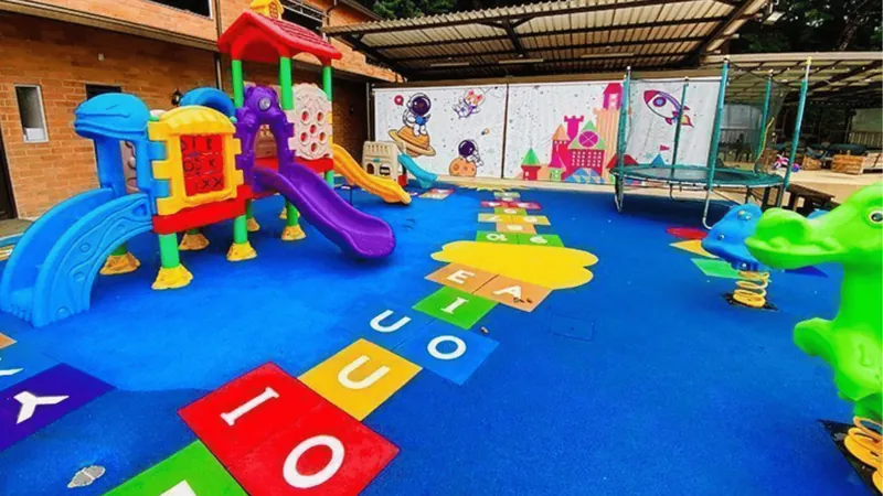 Zona de juegos infantil con piso de colores y rodaderos en la sede de Medellín