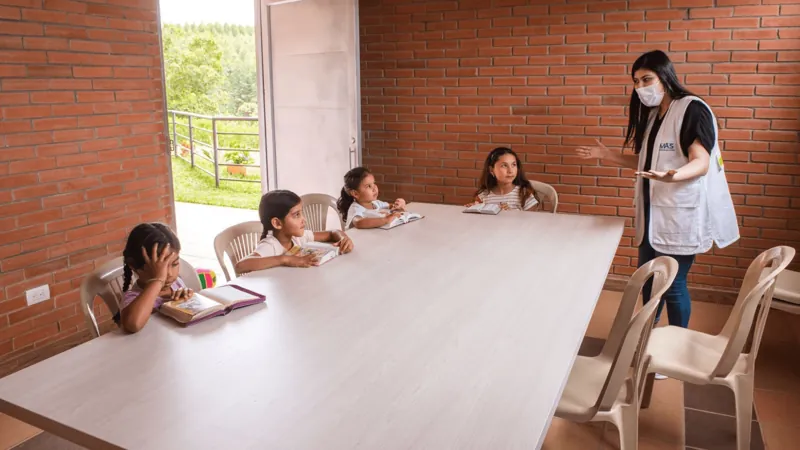 Niñas estudiando en una mesa con una profesora en la sede de Popayán